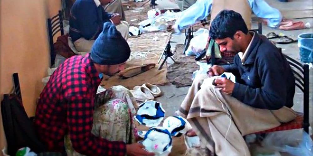 men sewing footballs